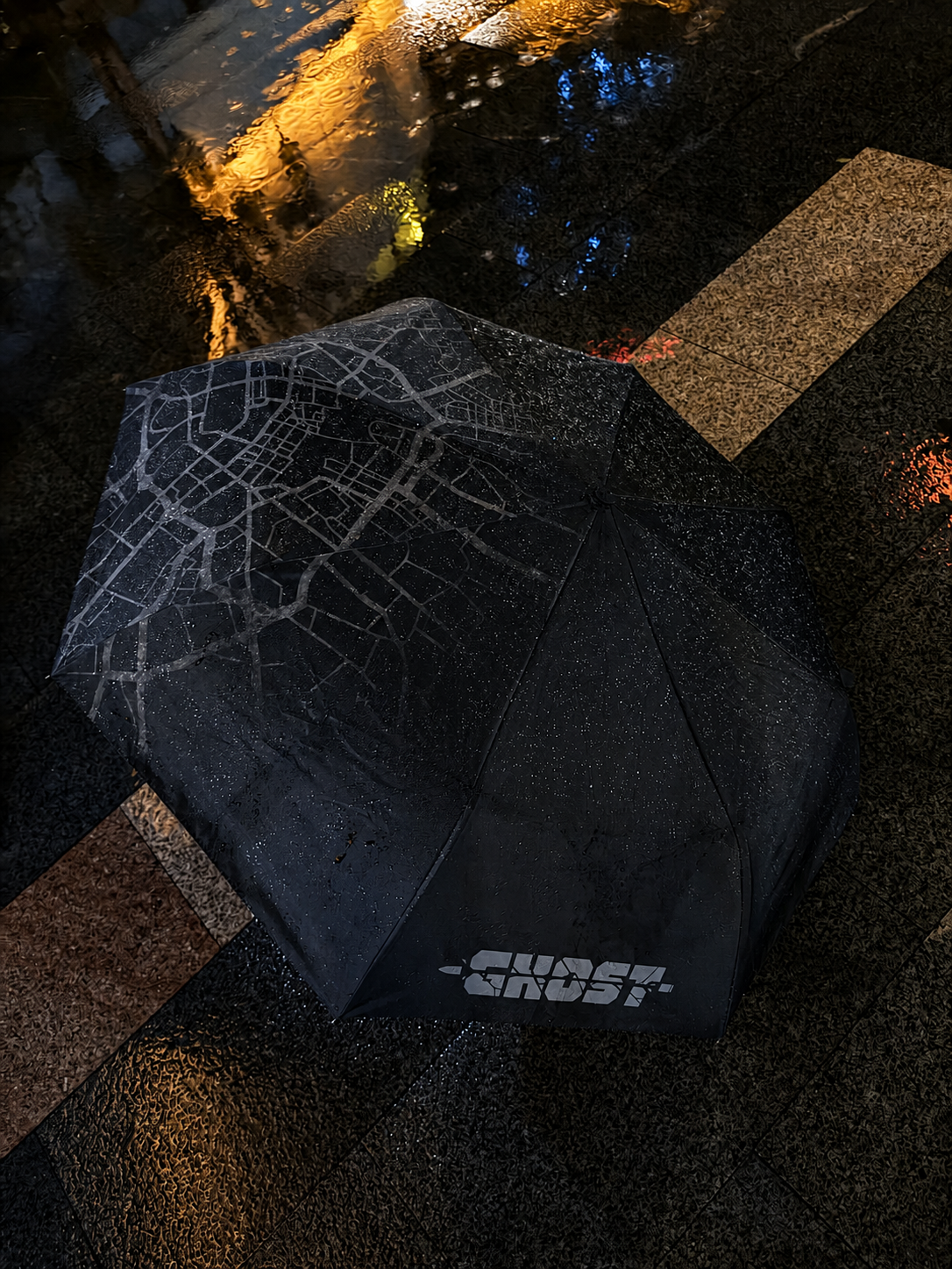 Black outer canopy of the Manchester Rainy Night umbrella on wet pavement, featuring a Manchester map pattern.