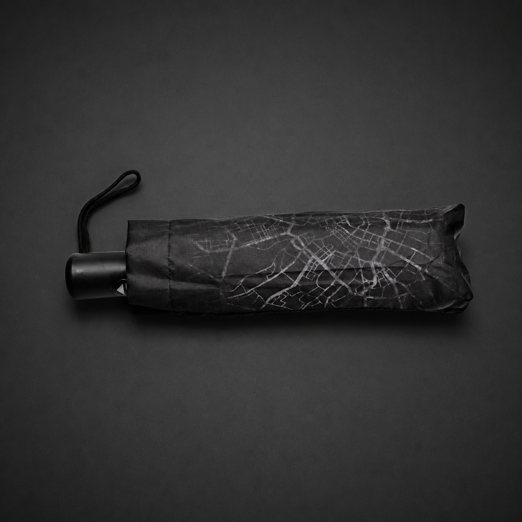 Folded umbrella showing the Manchester map pattern, black handle and wrist strap