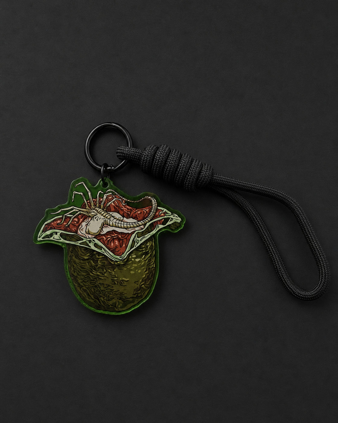 Alien Egg-inspired acrylic keychain with an open egg, Facehugger artwork and black adjustable loop strap
