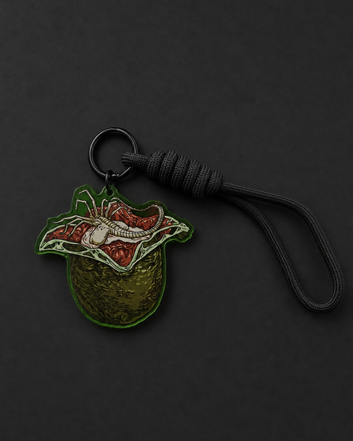 Alien Egg-inspired acrylic keychain with an open egg, Facehugger artwork and black adjustable loop strap
