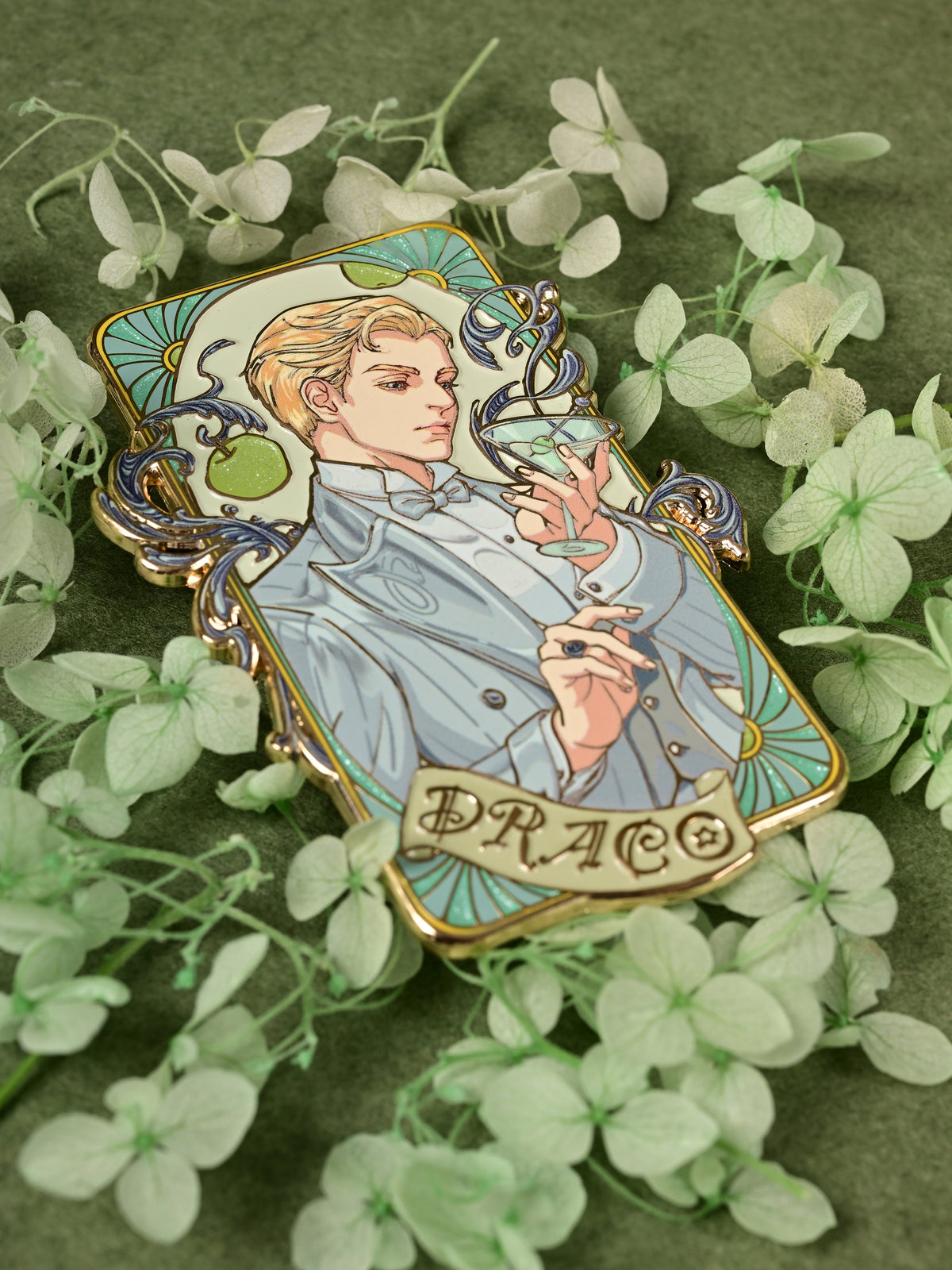 Jazz Age 1920 Darco enamel pin shown at an angle among pale green flowers on a dark green background